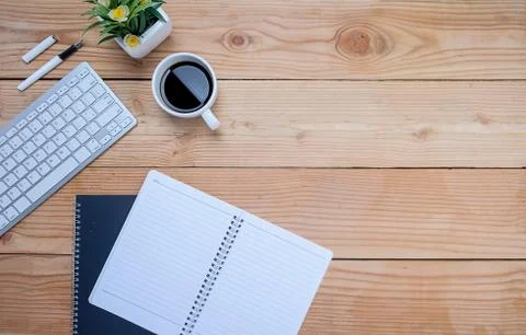Office desk table with keyboard, notebook, pen, cup of coffee and flower. Top Stock-Fotos