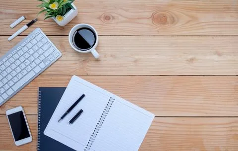 Office desk table with keyboard, notebook, pen, cup of coffee and flower. Top 스톡 사진