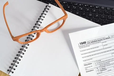 Office desk table with Laptop computer, eyegglass, 1040 taxform on notebook Stock Photos