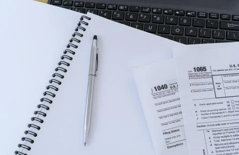 Office desk table with Laptop computer,pen, Tax forms 1040,1065 on notebook Stock Photos