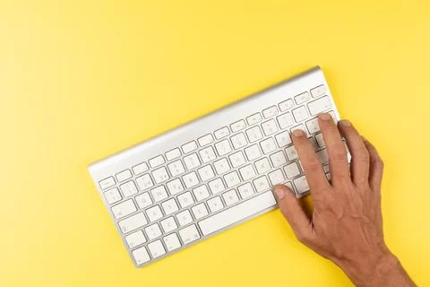 Office desk table Top view with keyboard and hand yellow background Stock Photos