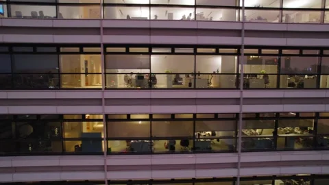 Office desks glimpsed through illuminated exterior windows in Guangzhou China Stock Footage 346032540