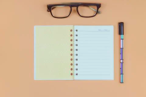 Office desktop with glasses, a white sheet for text, a notebook, a pen on the Photos