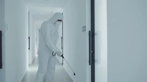 Office disinfection during COVID-19 pandemic. Man in protective suit and face ma Stock Footage