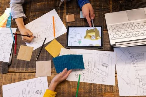 At office, diverse team using tablet, fabric samples, and sketches on table 写真素材