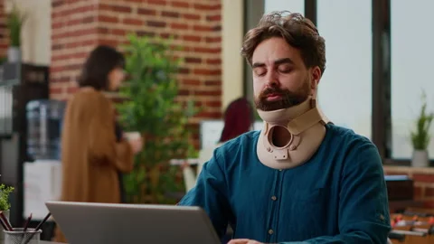 Office employee with neck collar brace working after accident injury Stock Footage