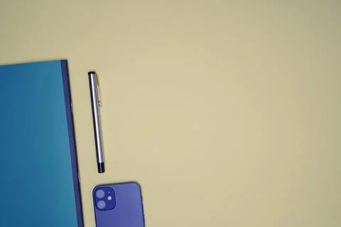 Office flat lay with pen, mobile and notebook placed on a light orange backgr Stock Photos