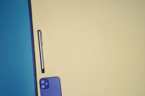 Office flat lay with pen, mobile and notebook placed on a light orange backgr Stock Photos