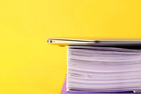 Office, folder with documents awaiting verification, laptop on a yellow backg Stock-Fotos