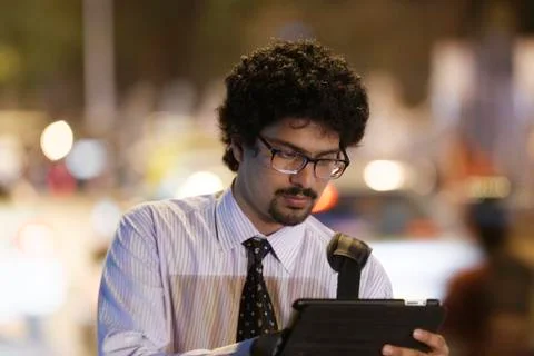 Office going young man using mobile phone, tablet on road. Stock Photos