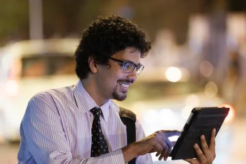 Office going young man using mobile phone, tablet on road. Stock Photos