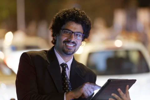 Office going young man using mobile phone, tablet on road. Stock Photos