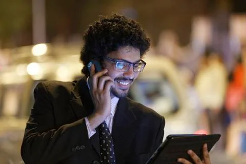 Office going young man using mobile phone, tablet on road. Stock Photos