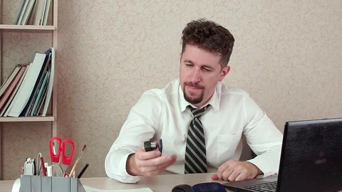 The office Manager of a bearded man bored at work, messing around with a stapler Video stock 100423454