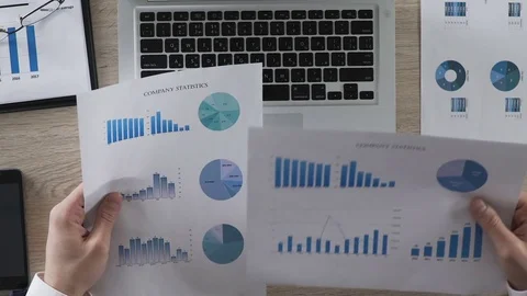 Office manager comparing statistical reports of company typing in data to laptop Stock Footage 76762043