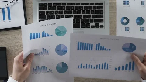 Office manager comparing statistical reports of company typing in data to laptop Stock Footage 76767155