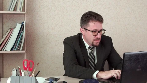 Office Manager man with beard and glasses. Works on a laptop. Stock-Footage 100403357