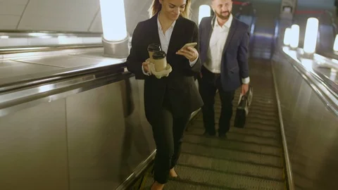 Office manager standing on escalator with smartphone Видео 120664394