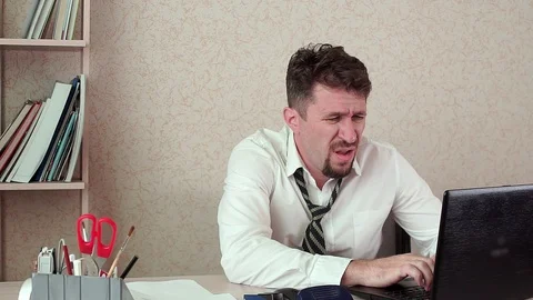 Office Manager tired man working on a laptop. He's hot and stuffy. Видео 100421428