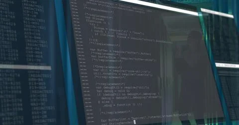 Office monitor displaying JavaScript code in dimly lit workstation, with glass Foto stock