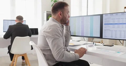 Office operator on phone at dual monitors, customer support and analytics Stock Footage 340405248