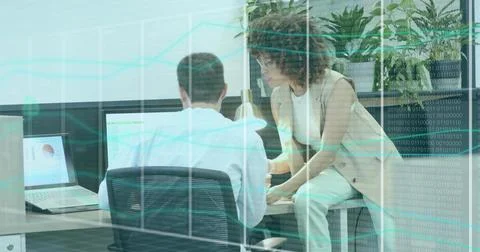 Office professionals reviewing data on computer screens in modern office, with Foto stock