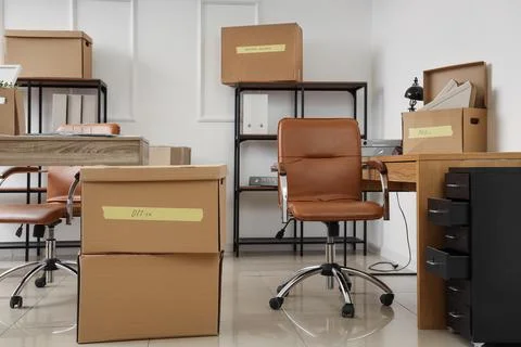 Office relocation and moving boxes with furniture in a bright empty room, bus Stock Photos