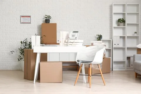 Office relocation and moving boxes in a modern workspace with white brick wal Stock Photos