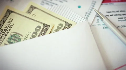 In office setting stack of one hundred dollar bills in envelope lies among s Stock Footage 336569878
