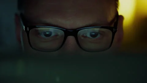 In an office space, lines of code flash on the monitor, reflected in the gla Stock Footage 259699766