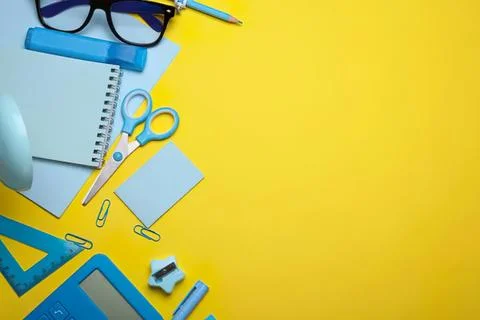 Office supplies on yellow background with notebook scissors and glasses Stock Photos