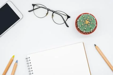 Office table with cactus, smartphone, notebook, eyeglasses and pencil, top vi Stock Photos