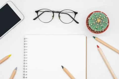 Office table with cactus, smartphone, notebook, eyeglasses and pencil, top vi Stock Photos