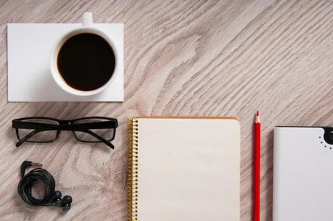 Office table with a coffee cup, a blank notepad and supplies Stock Photos
