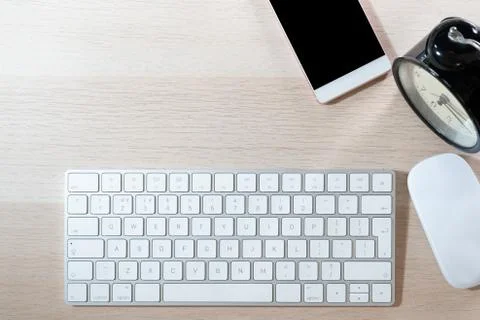 Office table with computer keyboard, mouse, smartphone and alarm clock. topvi Stock Photos