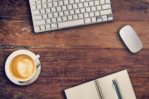 Office table with computer, notebook and coffee cup. View from above for vint Stock Photos