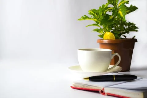 An office table with a cup of coffee, next to a notebook in a red note. Nearby Foto stock