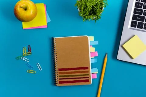 Office table desk with set of colorful supplies, white blank note pad, cup, pen Stock-Fotos