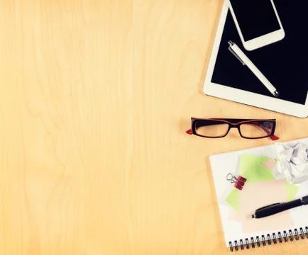 Office table with digital tablet, smartphone, reading glasses and notepad.  Stock Photos