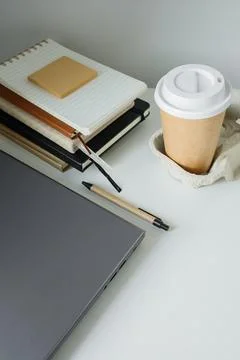 Office table flat lay: laptop, work note pads, pen, takeaway coffee in pape.. Foto stock