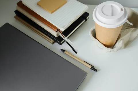 Office table flat lay: laptop, work note pads, pen, takeaway coffee in pape.. Stock-Fotos