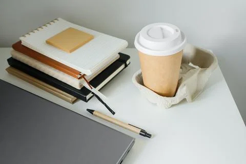 Office table flat lay: laptop, work note pads, pen, takeaway coffee in pape.. Stock Photos