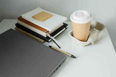 Office table flat lay: laptop, work note pads, pen, takeaway coffee in pape.. Stock Photos