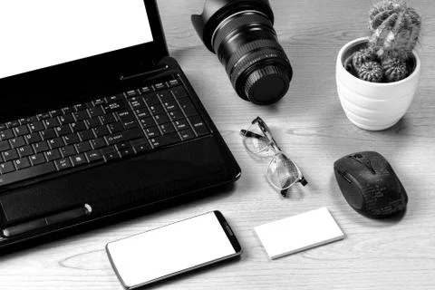Office table with laptop computer, camera lens, smartphone, eyeglass, mouse a Stock Photos