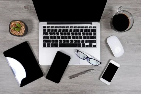Office table with laptop computer, digital tablet, pen, smartphone, mouse, ey Stock Photos