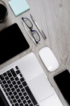 Office table with laptop computer, digital tablet, pen, smartphone, mouse, ey Stock Photos