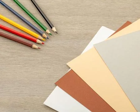 Office theme. Multi-colored pencils and sheets of colored paper are fanned ou Stock Photos