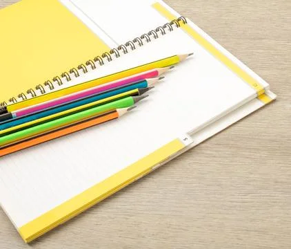 Office theme. Simple pencils with a multi-colored shell lie on an open notebook Stock Photos