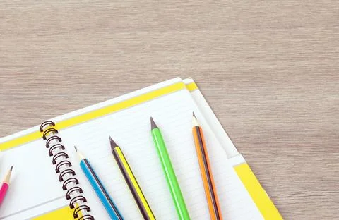 Office theme. Simple pencils with a multi-colored shell lie on an open notebook Stock Photos