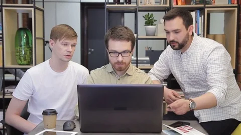 In the office, three men work quietly in front of one computer. Video stock 77550877